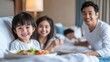 © Sasa Visual - A joyful Asian family is delighting in a room service breakfast, sharing smiles and food in their cozy hotel room in the morning