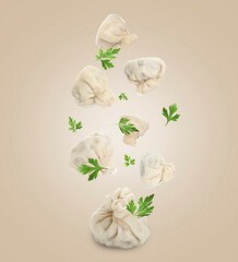 Wall Mural - Delicious khinkali (Georgian dumplings) and parsley falling on beige background