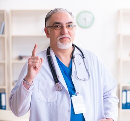 Wall Mural - Old male doctor working in the clinic