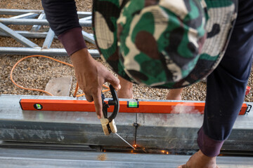 A man is sitting on the ground and working on a metal structure.