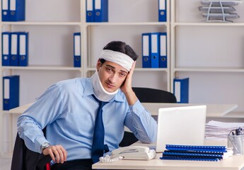 Wall Mural - Young injured male employee working in the office