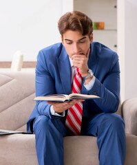 Poster - Young businessman working at home sitting on the sofa