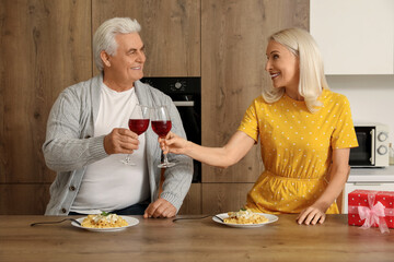 Poster - Mature couple drinking wine at table in kitchen