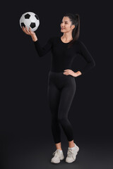 Wall Mural - Sporty young woman with soccer ball on black background