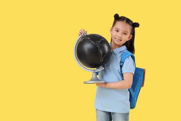 Poster - Cute little happy Asian girl with backpack and globe on yellow background. End of school year