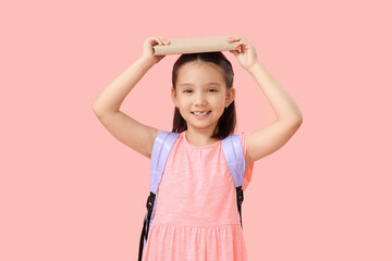 Poster - Cute little happy Asian girl with backpack and book on pink background. End of school year