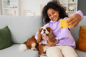 Canvas Print - Teen African-American girl taking selfie with cute cavalier King Charles spaniel at home