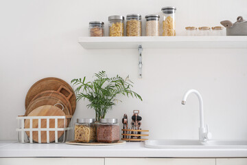 Cooking utensils with plant and sink on counter in kitchen