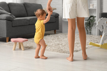 Poster - Cute little baby girl learning to walk with mother at home, back view