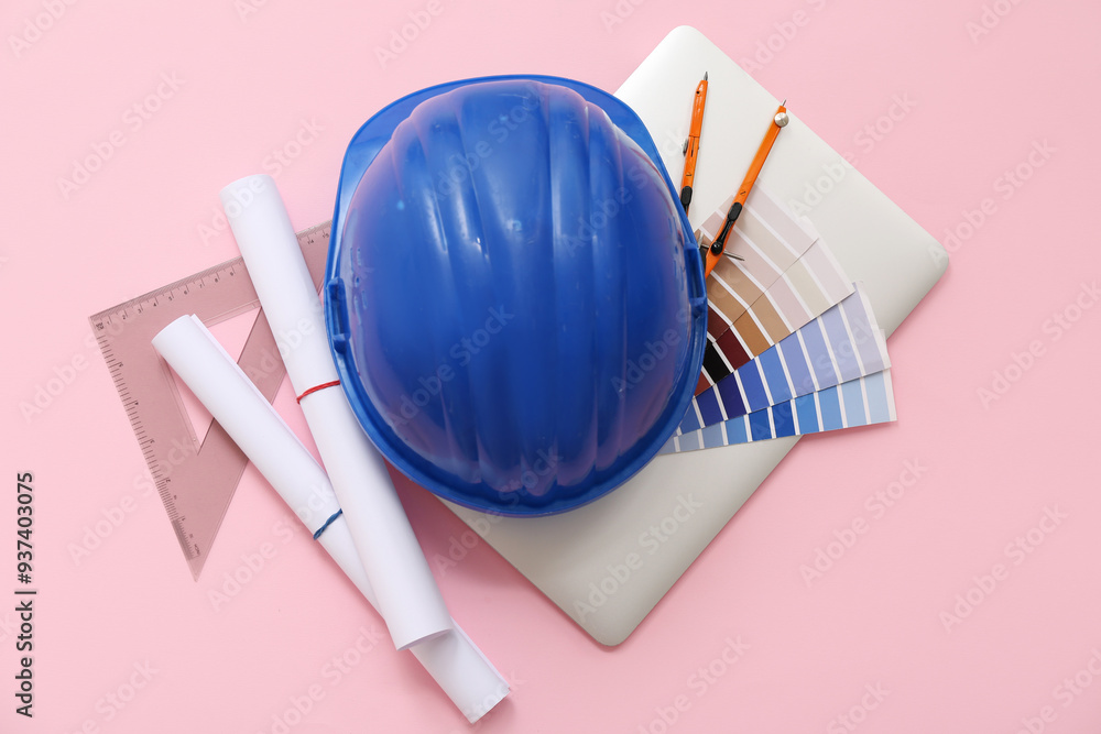 Architect's supplies with hardhat, laptop and house plan on pink background