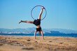 © Cavan Images - A person performs a handstand with a hula hoop on a beach