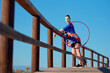 © Cavan Images - A performer showcases hula hoop skills along a coastal boardwalk