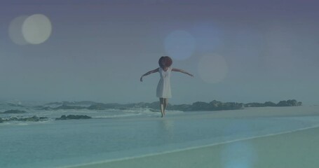 Poster - Woman standing with arms outstretched on beach over light bokeh animation