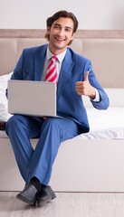 Poster - Young employee working at home sitting on the bed