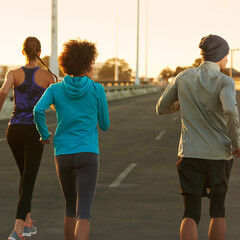 Wall Mural - Urban, road and people running at sunset together for fitness, training or commitment to body health. Evening, exercise and group of friends on street in city workout with outdoor challenge from back