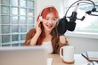 © wattana - Attractive young woman wearing headphones and speaks into a professional microphone,  recording a podcast in modern studio.