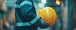 © alexandre - close-up image of a construction worker dressed in safety gear, holding a yellow hard hat securely
