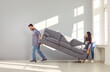 © Studio Romantic - Young family couple moving furniture in their new house or apartment. Man and woman buy a new sofa and put it in the living room. Happy husband and wife moving a new gray couch inside their apartment