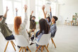 © Studio Romantic - Group of diverse happy young people sitting on chairs in circle and raising hands up. Friends, students or colleagues having fun together, voting for good idea, answering question on meeting. Teamwork