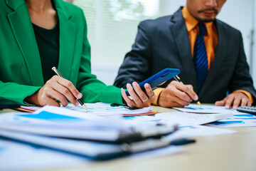 A group of professional business men and women are having a constructive meeting, discussing strategies, exchanging ideas and making decisions in a modern organization. They are wearing formal suits.
