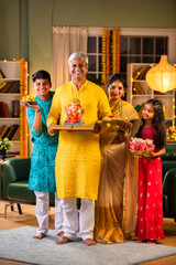 Indian family welcoming Ganpati idol Ganesh on Chaturthi in traditional attire