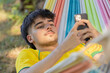 © carballo - young man or boy with mobile phone in summer lying in hammock