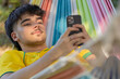© carballo - young man or boy with mobile phone in summer lying in hammock