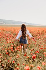 Canvas Print - Woman poppies field. Back view of a happy woman with long hair in a poppy field and enjoying the beauty of nature in a warm summer day.