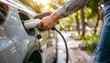 © Oleksiy - Electric car or ev is charging at station . man use the white power cable and plug on nature background