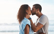 © Chanelle2000/peopleimages.com - Couple, embrace and kiss on beach for marriage romance, loyalty together and bonding with care. Woman, man and travel for relationship support, vacation anniversary and ocean date of blue sky outdoor