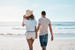 © Chanelle2000/peopleimages.com - Couple, back and holding hands at beach for travel, summer and tropical holiday together in San Diego. Man, woman and walking on sand by ocean for adventure, love and relax on vacation with partner