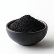© Sadaf - Black powder activated carbon, white background, black fine particles of charcoal in bowl on table, front view.