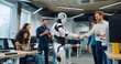 © ihorvsn - Multi-ethnic group of people surrounding their new creation in middle of large office room. Clapping together. In middle robot dancing before giving handshake to male. Showing thumbs up to camera.