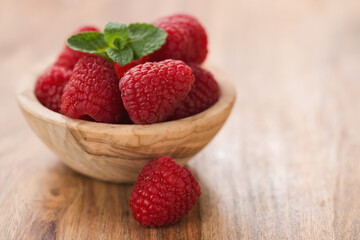 Wall Mural - fresh raspberries in wood bowl on table with copy space