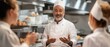 © INsprThDesign - A cheerful chef engaging with his team in a bustling kitchen, sharing culinary insights and fostering teamwork and creativity.