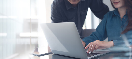 Canvas Print - Two business person together working, analyzing business data on laptop computer at office. Startup business teamwork, colleague using laptop, meeting and sharing ideas, partnership, teamwork concept