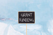 © Dzmitry - Grant funding symbol. Concept words Grant funding on beautiful yellow black blackboard. Beautiful blue ice background. Business and grant funding concept. Copy space.