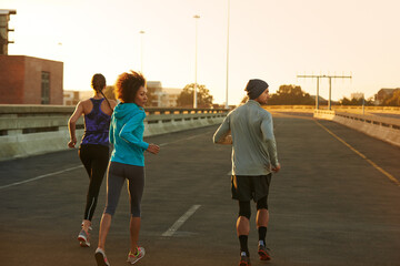 Poster - City, street and people running at sunset together for fitness, training or commitment to body health. Evening, exercise and group of friends on road in urban workout with outdoor challenge from back