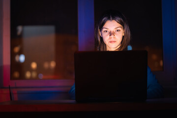 Girl works on a laptop at home at night.