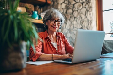 Mature woman using pc laptop indoor - Senior female smart working with computer at home - She is sitting on a wooden modern desk at home. Smiling and enjoying, Generative AI