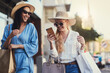 © peopleimages.com - Phone, friends and happy women with shopping bags in city for fashion sunglasses, discount or credit score. Mobile, girls and gift outdoor at mall for retail promo, account payment or online banking