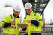 © Supachai - Two male petrochemical engineers with walkie-talkie and tablet working and discussing inspection and maintenance plans for pipelines for oil and gas at petroleum refinery, power plant energy industry.