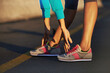 © peopleimages.com - Runner, stretching and legs on road for fitness, sneakers and ready for exercise. Athlete, person or hands on feet in street for wellness, training or running shoes for sport or outdoor activity