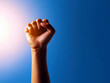 © Narongsak - A raised fist symbolizes strength and solidarity, representing resilience and the fight for justice. Against a vibrant blue background, it embodies hope and determination in overcoming challenges.
