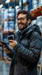 © Kowit - A man wearing a black coat and glasses is smiling while holding a cell phone