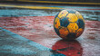 © Sawyer0 - Kolorowa, zużyta piłka znajduje się na mokrym, wielokolorowym boisku, przywołując poczucie nostalgii i trwałego uroku sportów.