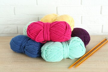 Wall Mural - Skeins of yarn and knitting needles on wooden shelf near white brick wall