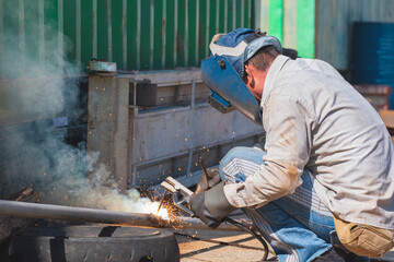 welder is welding galvanized steel pipe for improvement building structure at outdoor workshop in co