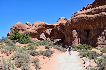 Wall Mural - Woman on short trail to Double Arch in Arches National Park near Moab, Utah on clear sunny summer morning.