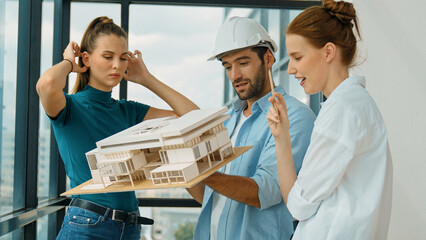 Wall Mural - Skilled engineer holds house model and explain about house construction to skilled manager. Group of interior designer inspect architectural model. Working together, Civil engineering. Tracery